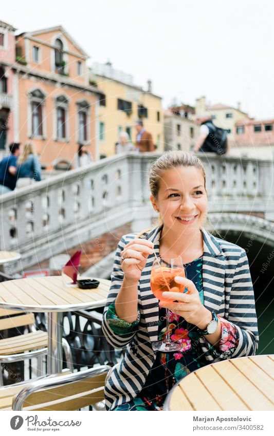 Junge Reisende genießt ein Glas Spritz in einem Freiluftcafé in Venedig, Italien Erwachsener Alkohol Aperitif Aperol Getränk Brücke Café Kaukasier heiter