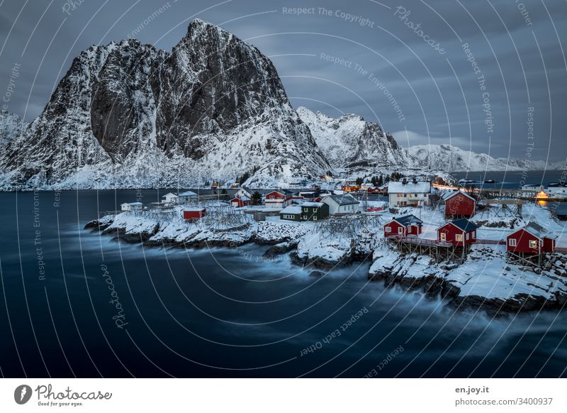 Hamnoy auf den Lofoten mit Aussicht auf die kleinen roten Häuschen die auf verschneiten Felsen stehen zur blauen Stunde Ferien & Urlaub & Reisen Ausflug Winter