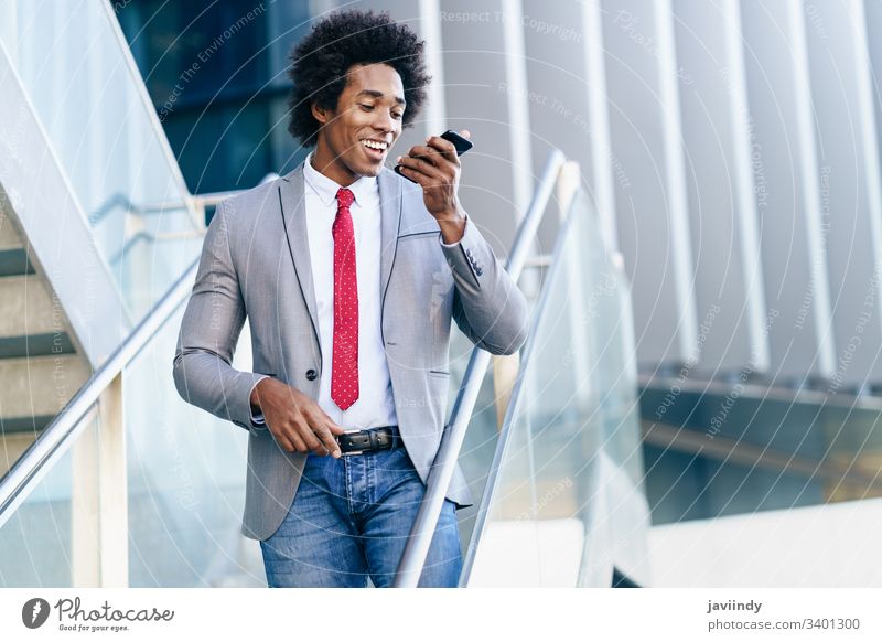 Schwarzer Geschäftsmann mit einem Smartphone in der Nähe eines Bürogebäudes schwarz lockig Afro-Look Business du Behaarung Anzug Afrikanisch männlich