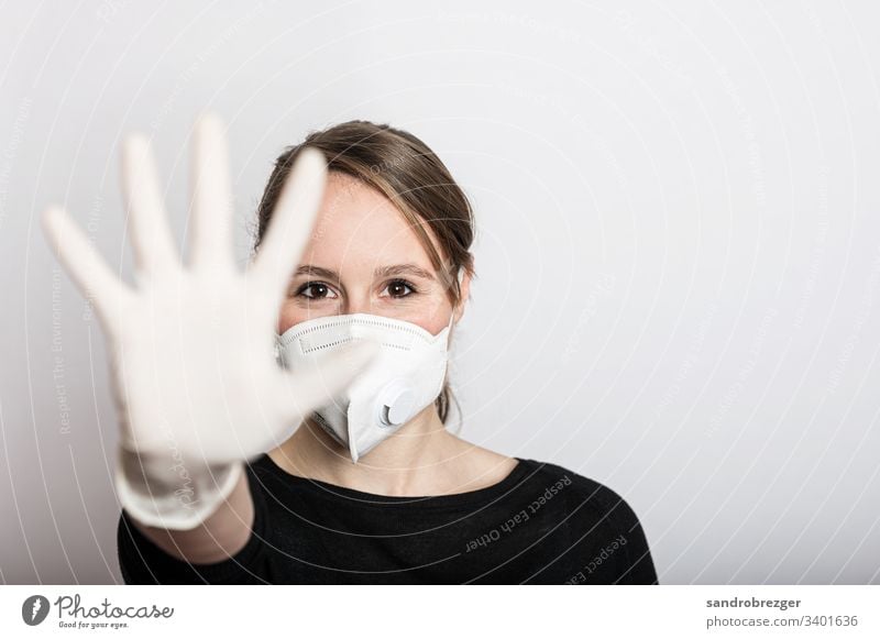 Frau mit Mundschutz und Handschuhen stoppt die Corona Virus Epidemie Coronavirus COVID-19 Krankheit Pandemie Maske Schützen Einmalhandschuhe Handschutz Steril