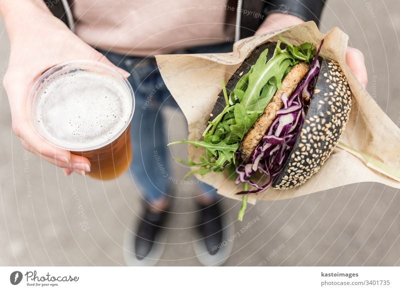 Frauenhände mit köstlichem vegetarischen Bio-Lachsburger und selbstgebrautem IPA-Bier. Burger Hände Salat Essen organisch Fleisch ungesund Grillrost Alkohol