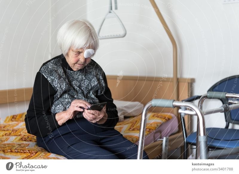 Einsame ältere Frau, 95 Jahre alt, die mit einem modernen Mobiltelefon am Schlechten sitzt. Senior Rentnerin Pflege Behinderung Krankenhaus Mobilität heimwärts