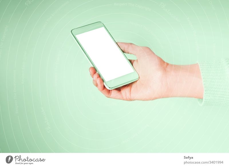 Hand mit Mobiltelefon und leerem weißen Bildschirm auf mintgrüner Farbe 2020 grüne Minze Mobile Telefon neo benutzend Farbe Jahr Hände Smartphone Frau Gerät