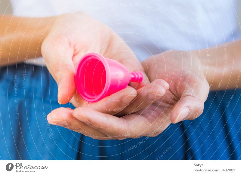 Frau hält eine rosa Menstruationstasse in den Händen. Nahaufnahme Tasse menstruell keine Verschwendung Produkt Aussehen Beteiligung Hygiene wiederverwendbar