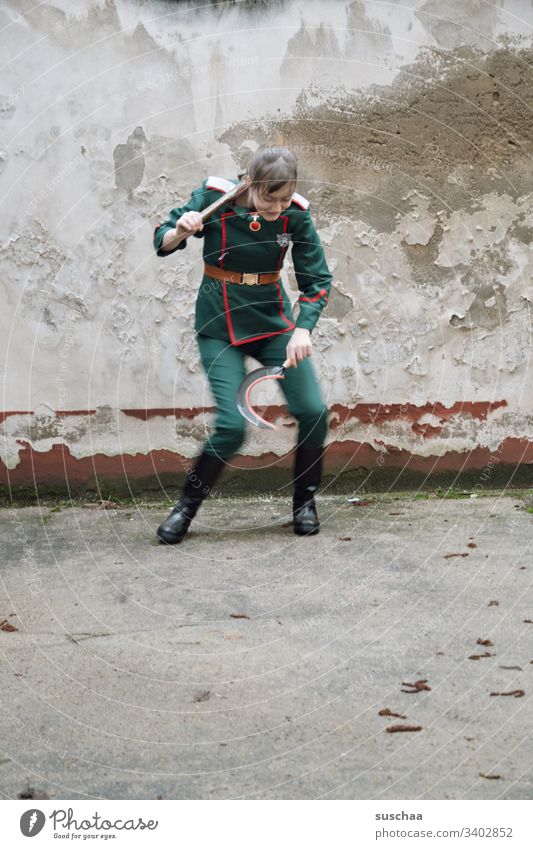 jugendliche in uniform mit sichel und hammer in der hand macht ein seltsames tänzchen Mädchen junge Frau Jugendliche Teenager Pubertät Uniform Anzug Sichel