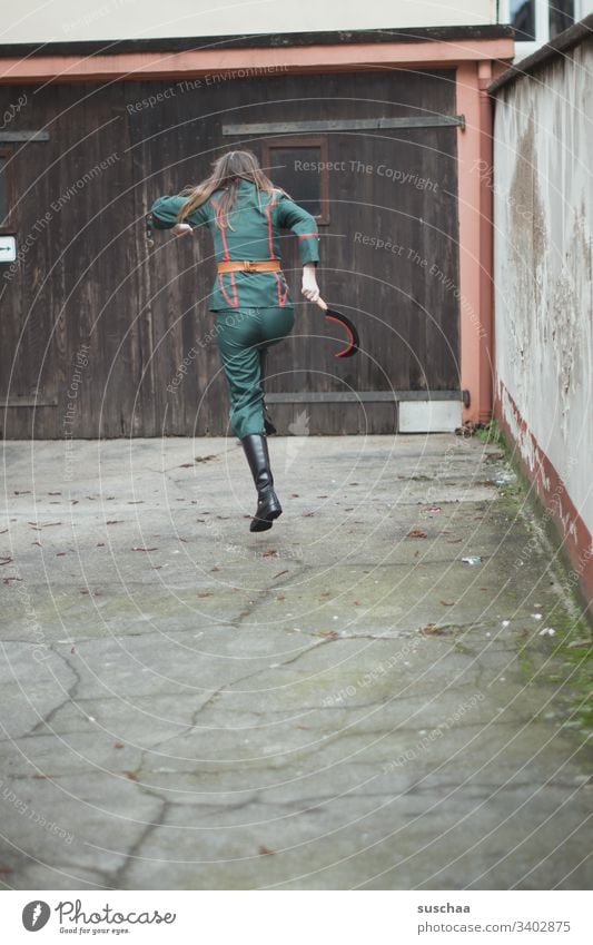 teenager in uniform hüpft mit einer sichel in der hand über im innenhof Mädchen junge Frau Jugendliche Teenager Pubertät Uniform Anzug Sichel Hammer Werkzeug