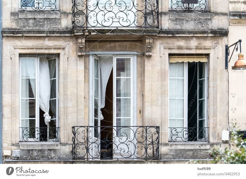 eleganter Altbau Balkon mit offenen Fenstern und wehenden Gardinen Vorhängen Fensterladen Reihe Natursteinfassade Mauer Wand Bogenfenster Zentralperspektive
