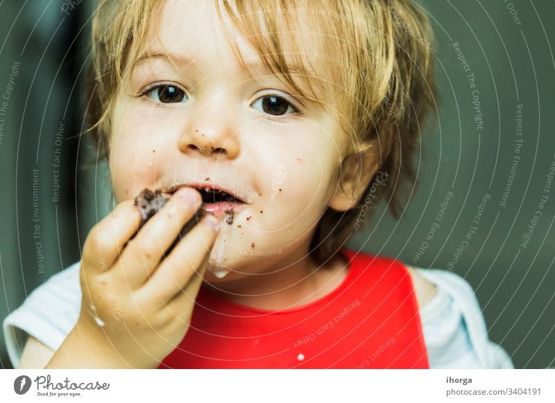 Porträt bezauberndes Kind isst Schokolade Biskuitkuchen Attribut Baby Hintergrund Lätzchen Junge braun Kuchen Bonbon Kindheit schoko niedlich lecker wüst