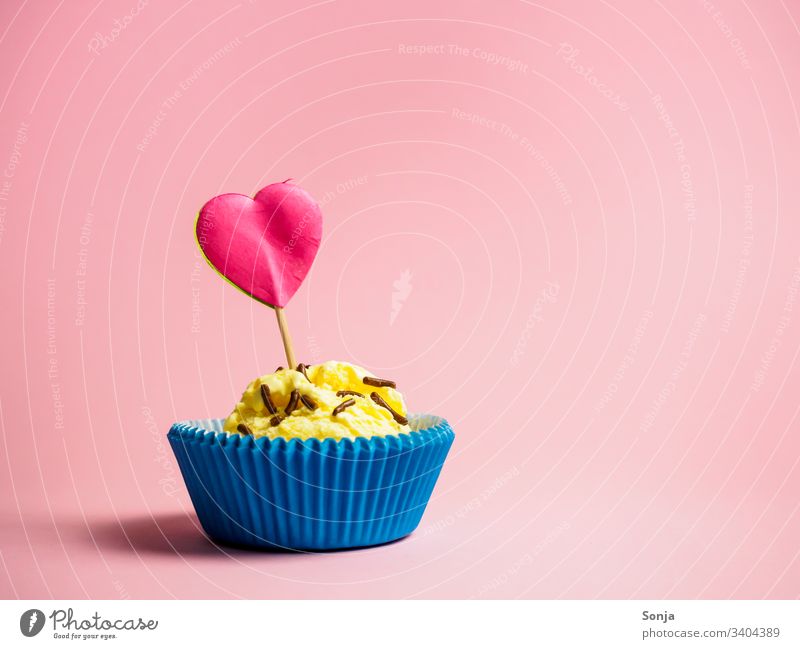 Vanilleeis in einer blauen Muffinform mit einem pinken Herzen auf einem rosa Hintergrund vanilleeis Eis muffinform herz Papier Farbfoto Sommer liebe geburtstag