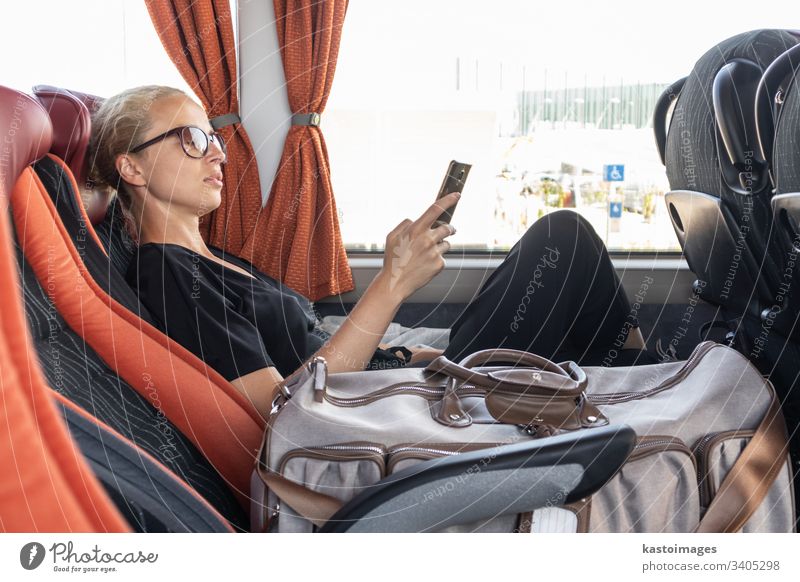 Porträt einer Frau, die im fahrenden Bus am Fenster sitzend mit dem Handy telefoniert. Passagier Pendler Arbeitsweg Mädchen Transport im Inneren Reise Menschen
