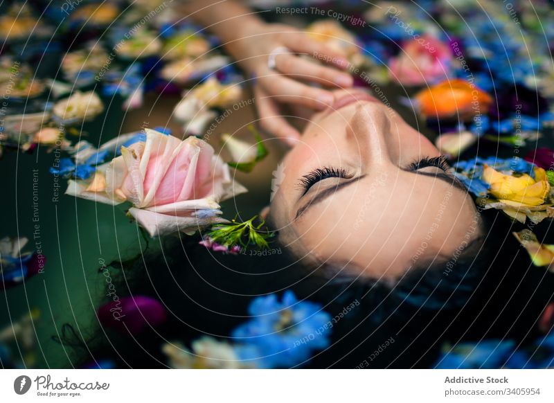 Sinnliche Frau mit Blumen im Wasser liegend Badewanne Spa Schönheit Angebot Gesicht berühren elegant Leckerbissen Blüte Waschen sich[Akk] entspannen ruhen