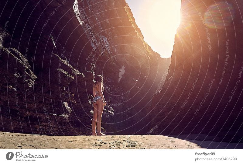 Junge Frau im Bikini, die eine Felsformation am Strand betrachtet Tourismus wandern Galicia Spanien Ribadeo Castros Illas Felsen atlantisch Bucht touristisch
