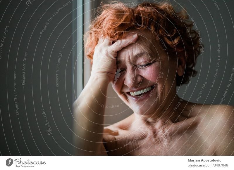 Glückliche reife Frau lächelt am Fenster 60s Erwachsener Lebensalter gealtert Alterung attraktiv schön Schönheit Pflege sorgenfrei Kaukasier charmant heiter