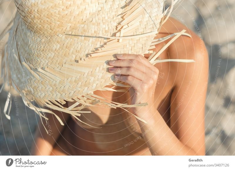 junges Mädchen mit Strohhut sitzt auf dem Sand am Strand aus nächster Nähe Körper Klima Nahaufnahme Tag Frau weiblicher Körper Finger Freiheit Hände Hut Kopf