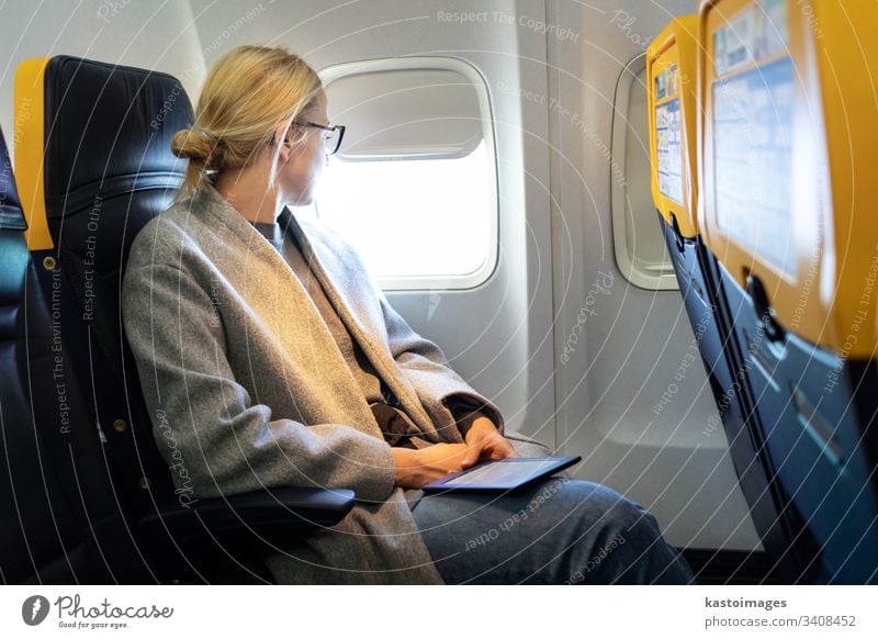 Nachdenkliche Frau, die während einer Flugreise durch das Fenster schaut. Flugzeug Ebene reisen Sitz Kabine im Inneren Fluggerät Passagier E-Reader nachdenklich
