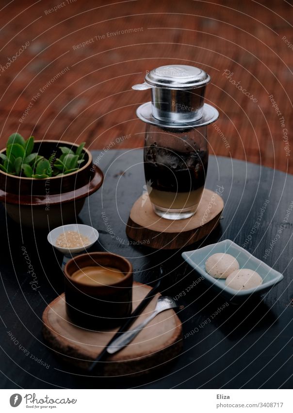 Traditioneller vietnamesischer Kaffee mit einem Tassenfilter serviert auf einem Tisch in einem Café phin Einzel-Tassen-Filter Kondensmilch Eiskaffee Espresso