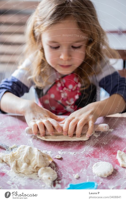 Hübsches blondes kleines Mädchen spielt mit Teig schön wenig lockig Behaarung backen Essen zubereiten Spielen Teigwaren Nudelholz abschließen Hände Süßigkeiten