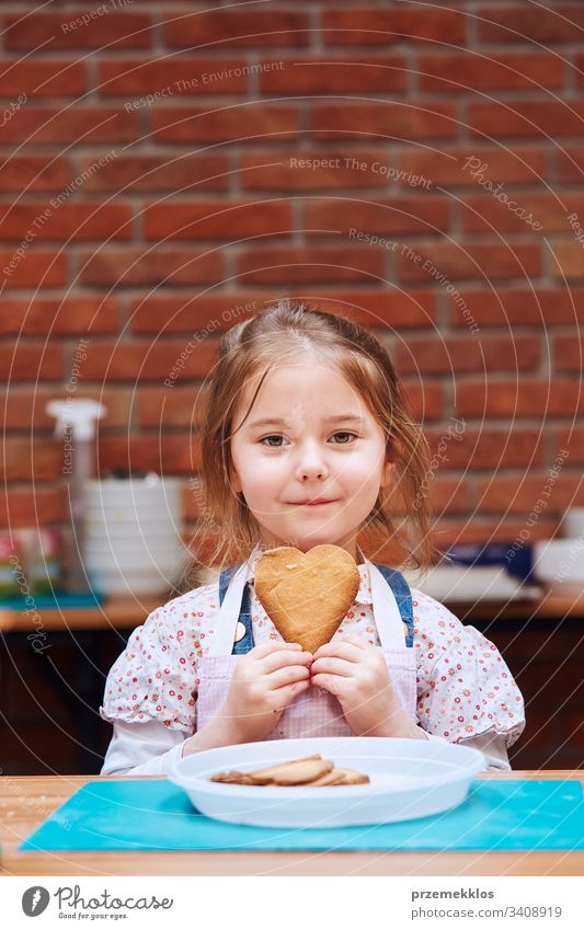 Ein kleines Mädchen, das sich über einen gebackenen Keks freut, hat sich selbst gemacht. Kind, das am Backworkshop teilnahm. Backkurse für Kinder, aufstrebende kleine Köche. Lernen, wie man kocht. Kombinieren und Rühren von vorbereiteten Zutaten. Echte Menschen, authentische Situationen