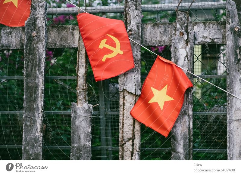 Ein Zaun an dem die vietnamesische Nationalflagge, mit Hammer und Sichel in gelb auf rotem Hintergrund, hängt; Symbol für Kommunismus Flagge Sozialismus Vietnam