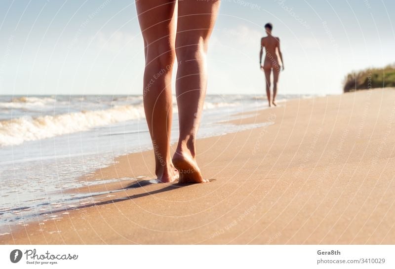 nackte junge Mädchen gehen an einem Sommertag am Strand in den Wellen der Brandung Rücken Körper Körperteil Klima Klamotten aus Paar Tag Fuß Frau Freiheit heiß