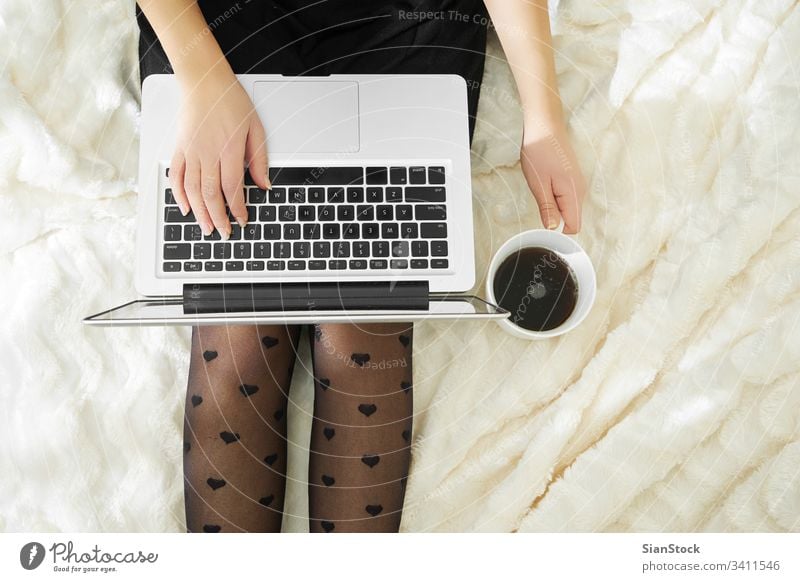 Junge Frau trinkt zu Hause in ihrem Bett Kaffee und schaut auf ihren Laptop Computer Tasse heimwärts jung Mädchen benutzend weiß schön Technik & Technologie