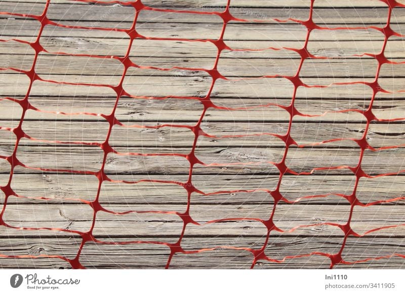 Folienband rot als Gitter ausgestanzt versperrt Durchgang zum grauen Holzsteg Plastik Kunsttofffolie stanzen Absperrung Warnung betreten verboten Gefahr Zaun