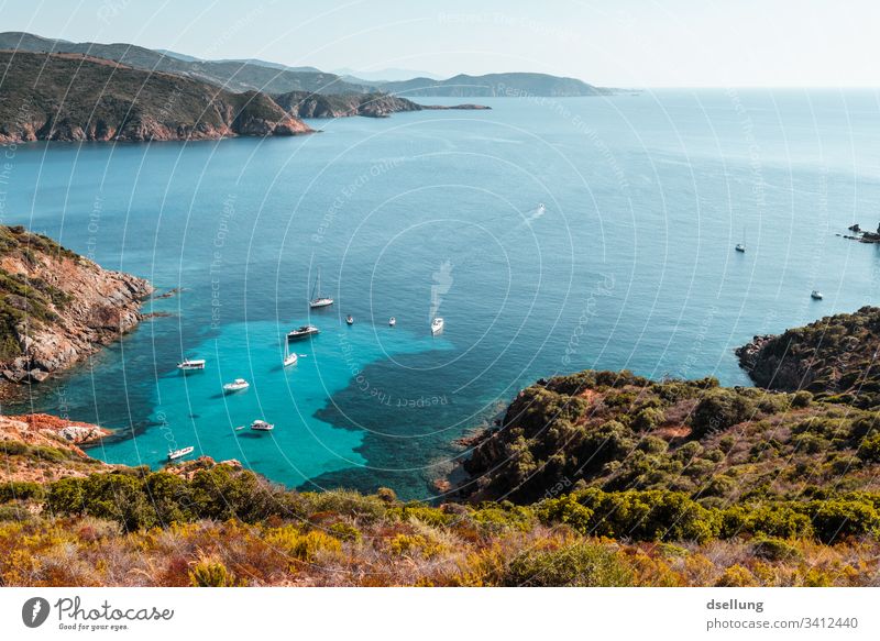 Türkises Meer mit Schiffsverkehr von einer Halbinsel aufgenommen mit Gebirgsarmen türkis blau grün braun Landschaft Urlaubsstimmung Korsika Bootsfahrt Himmel