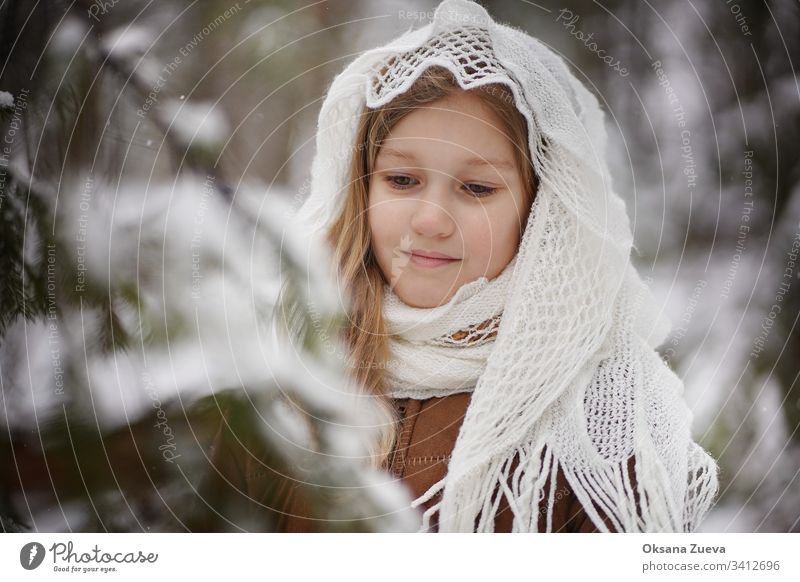 Ein 7-jähriges Mädchen in einem braunen Schafsfellmantel im Winterwald. Konzept der Jahreszeiten, ein Wintermärchen. Schnee, Bäume. Baby Hintergrund schön