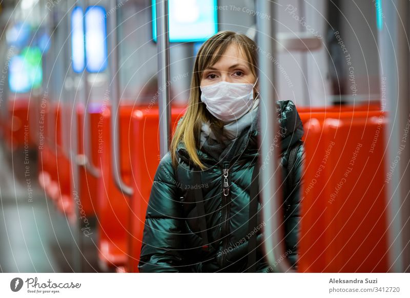 Frau im Wintermantel mit Schutzmaske auf dem Gesicht steht im U-Bahn-Wagen, telefoniert und sieht besorgt aus. Präventivmassnahmen an öffentlichen Orten von Epidemiegebieten. Finnland, Espoo
