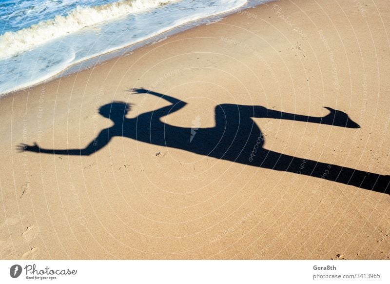 Schatten eines tanzenden Mädchens auf dem Seesand am Strand in der Nähe des Meeres schwarz blau tanzender Schatten Hände ruhen Sand MEER Schatten eines Mädchens