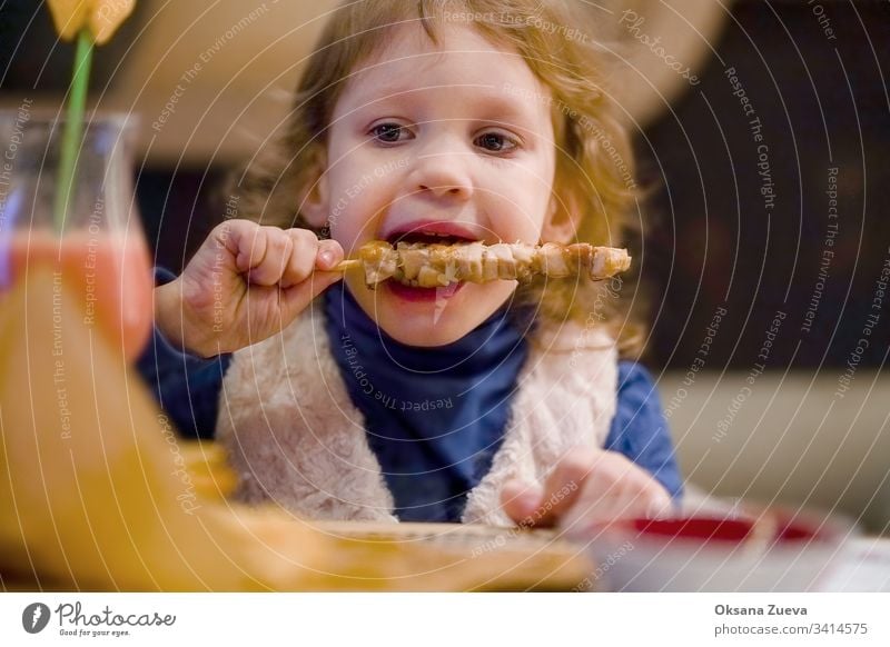 Kleines gelocktes Mädchen isst Hühnchen in einem Cafe bezaubernd Baby Café Kaukasier Kind Kindheit Kinder lockig niedlich lecker Abendessen