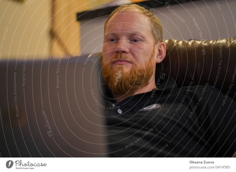 "Moskau / Russland - Dezember 2019: Volvo-Mitarbeiter sitzt zu Hause auf der Couch und arbeitet am Computer und arbeitet von zu Hause aus mit einem Coronavirus".