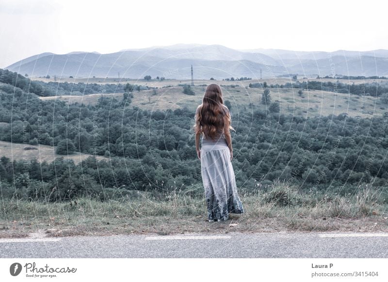 Einsame Frau mit langen Haaren, die auf einen Hügel schaut sorgenfrei glauben Sprit Gedanken Wind Behaarung träumen Tag Hintergrund Gras Erwachsener Blick