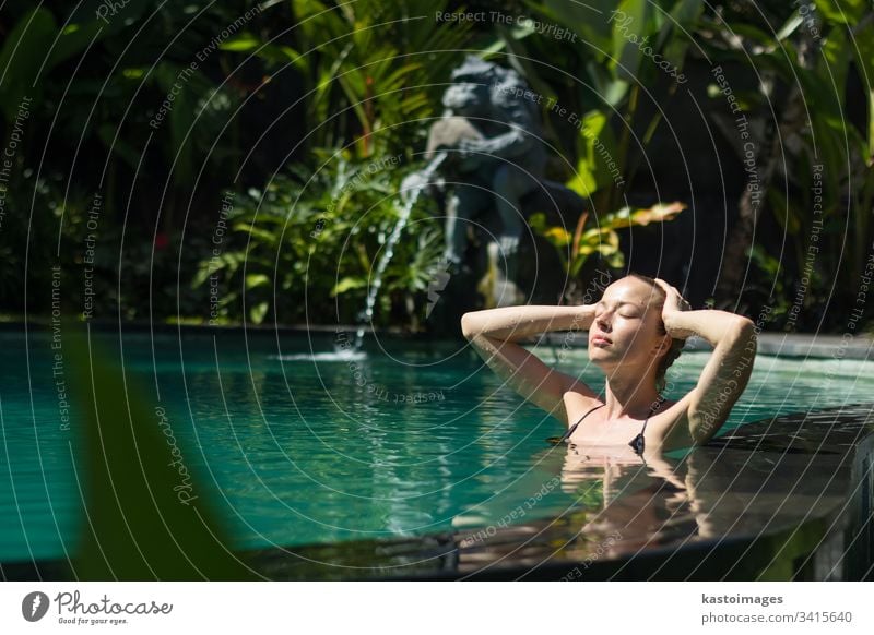 Sinnliche junge Frau entspannt sich im Infinity-Spa-Pool im Freien, umgeben von üppigem tropischem Grün in Ubud, Bali. Wellness Wasser Natur Schwimmsport