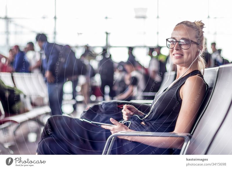 Eine weibliche Reisende, die ihr Handy benutzt, während sie an den Abfluggates des asiatischen Flughafenterminals auf das Einsteigen in ein Flugzeug wartet.