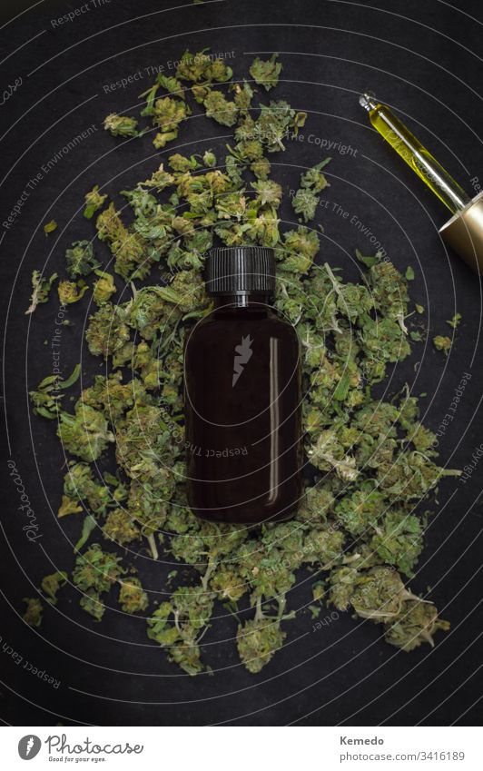 Berg von Marihuana-Knospen mit einer Flasche CBD-Make mit Cannabis oben isoliert auf schwarzem Hintergrund. CBD oder Cannabidiolprodukt. cbd Erdöl Unkraut