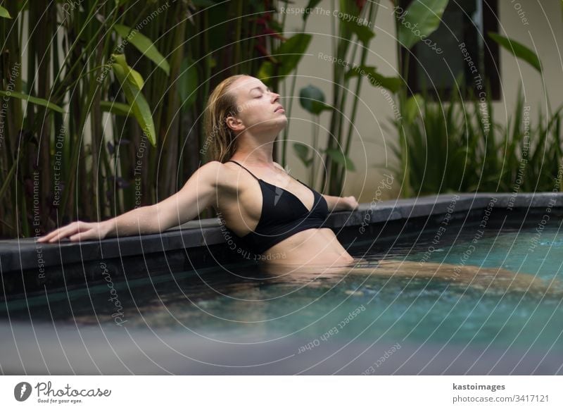 Sinnliche junge Frau entspannt sich im Infinity-Spa-Pool im Freien, umgeben von üppigem tropischem Grün in Ubud, Bali. Wellness Gelassenheit sinnlich Erholung
