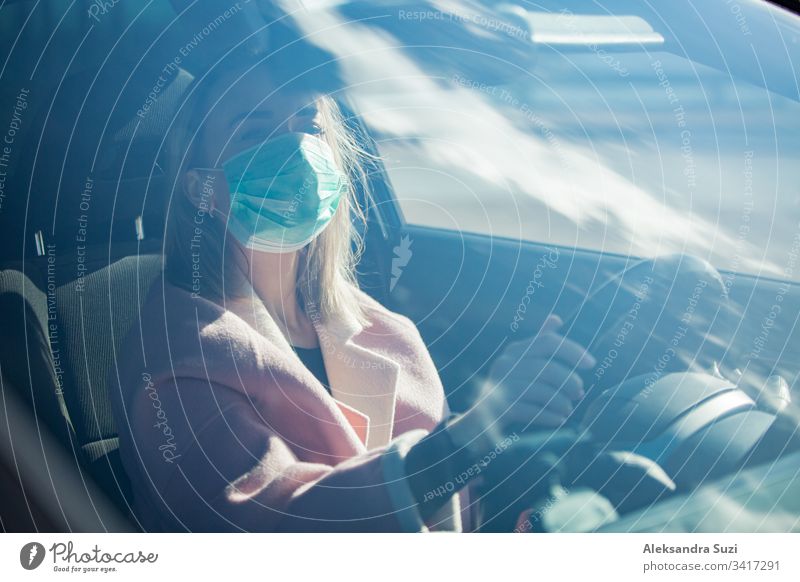 Frau mit Schutzmaske, die ein Auto auf der Straße fährt. Sicheres Reisen. Automobil Atmung PKW Großstadt Coronavirus covid-19 Armaturenbrett Ausflugsziel