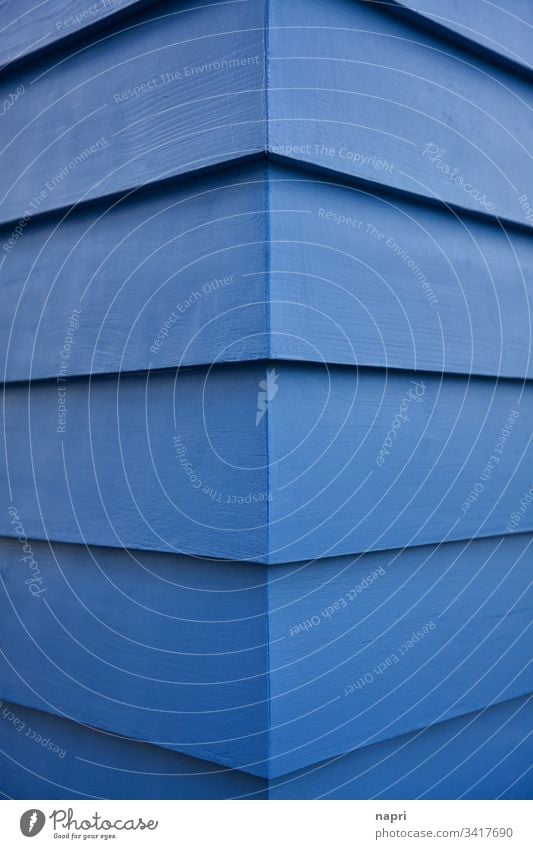 Ecke eines Gebäudes dessen Fassade mit blau gestrichenen Holzbrettern verkleidet ist. Blau Abstrakt Architektur Kante Linien geometrisch Hintergrund Haus Muster