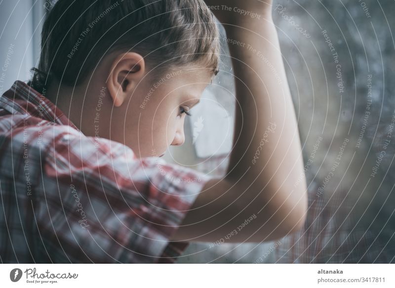 Porträt eines traurigen kleinen Jungen, der in der Nähe eines Fensters sitzt Unschuld schlecht Trauer Probleme Jugend Verlust Problematik verirrt deprimiert