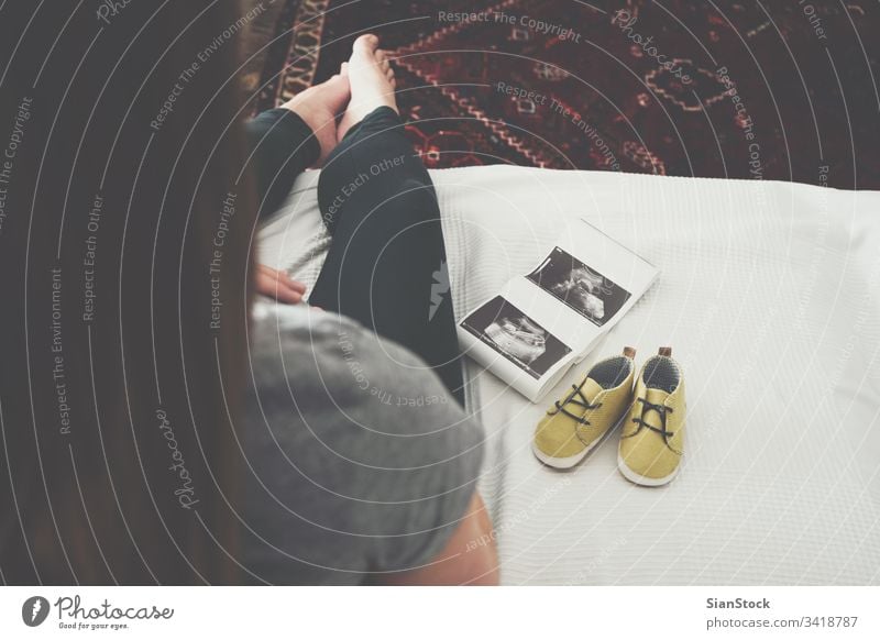 Junge schwangere Frau entspannt sich auf dem Sofa Schwangerschaft Baby Bauch heimwärts Ultraschall-Scan Mutterschaft erwartend Glück Top Ansicht Schuhe gelb