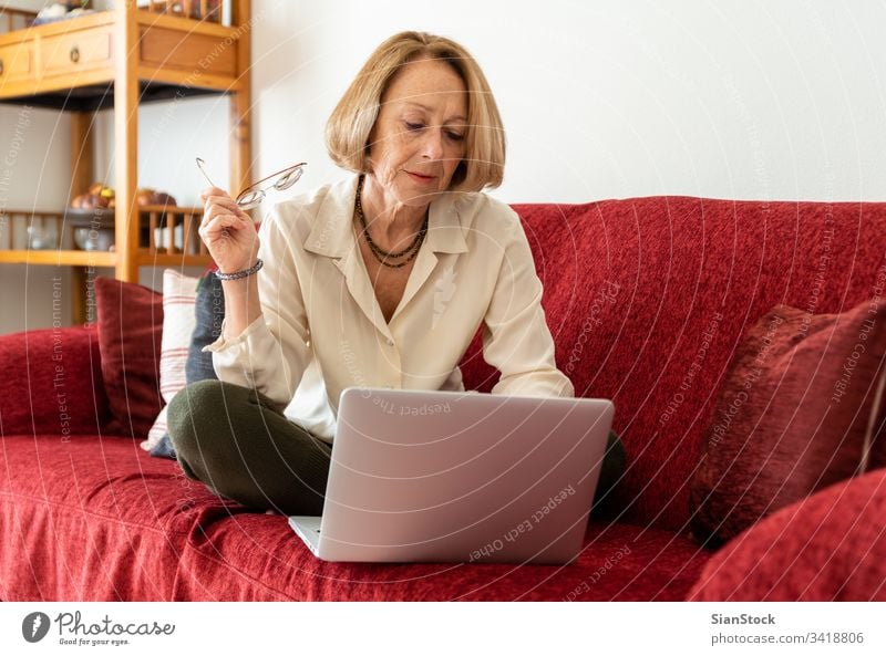 Elegante, reife Frau, die zu Hause einen Computer benutzt älter Dame gealtert Schönheit Wohlbefinden sorgenfrei Komfort attraktiv bequem lässig blond entspannt