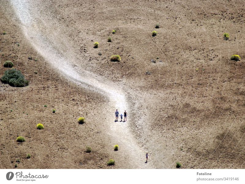 Der Weg ist das Ziel - oder ein Weg in einer wüstenartigen Umgebung auf dem winzige spazierende Menschen am Fuße des Teide im Teide Nationalpark auf der spanischen Insel Teneriffa zu sehen sind