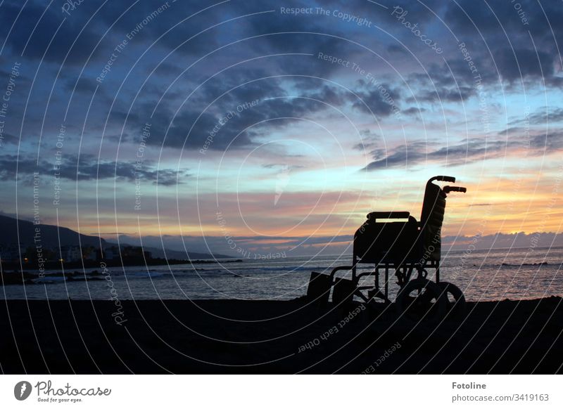 Rollstuhl am Strand von Puerto de la Cruz auf Teneriffa im Sonnenuntergang Berge u. Gebirge Landschaft Außenaufnahme Himmel Natur Farbfoto Menschenleer Wolken