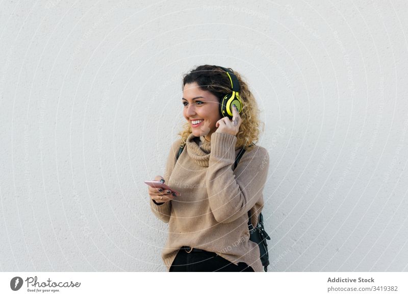 Zufriedene Frau mit Kopfhörern und Smartphone benutzend Lächeln lässig Lachen genießen Inhalt zuhören Musik Gerät Apparatur modern Kommunizieren Anschluss