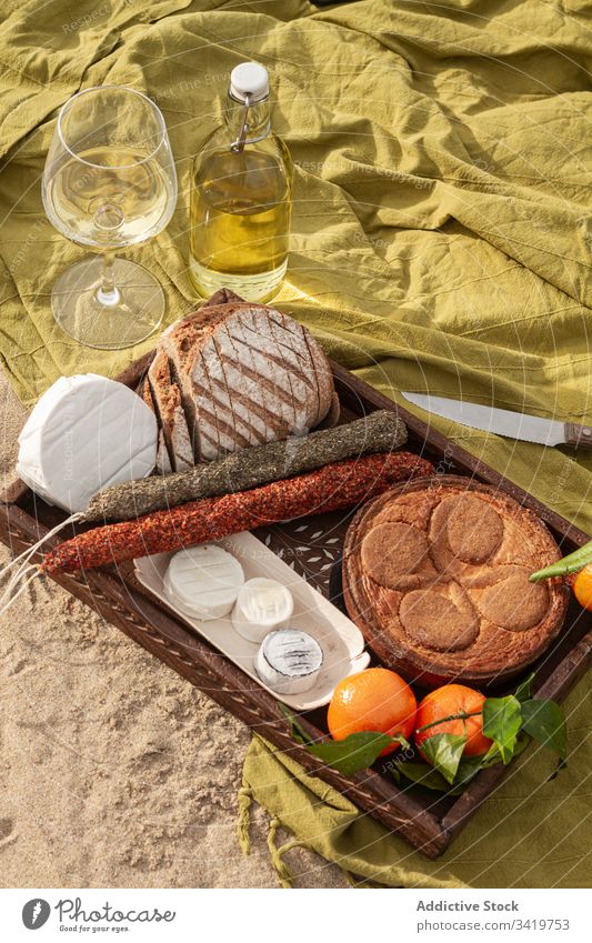 Gebäck und Mandarinen mit Käse und Würstchen in der Nähe von Wein während des Picknicks Lebensmittel Decke Strand Pasteten Brot Wurstwaren lecker geschmackvoll