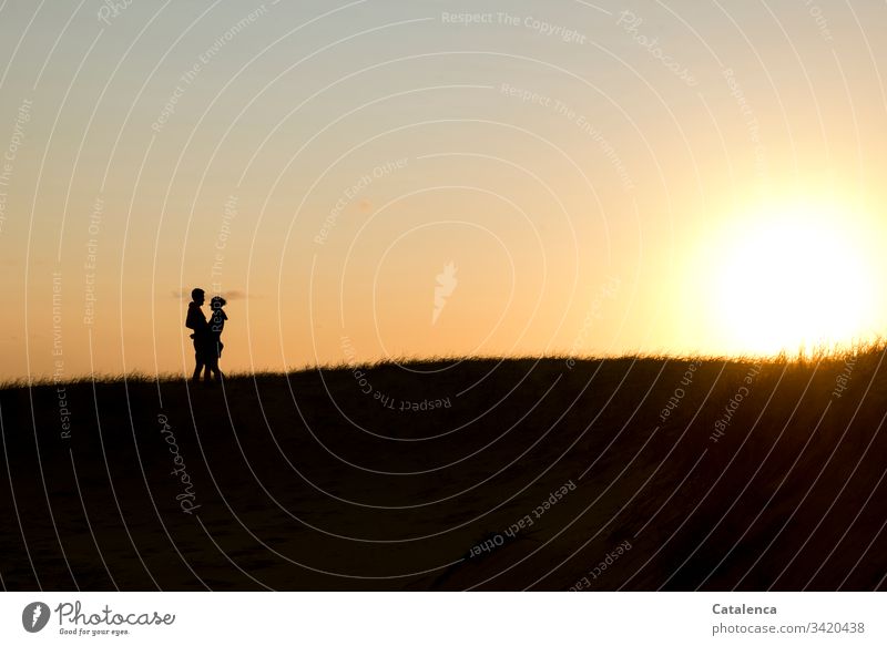 Die Sonne geht am Horizont  unter, links die Silhouette eines sich umarmenden Paares Sonnenuntergang Dämmerung Abend Wolken Himmel Abenddämmerung Natur