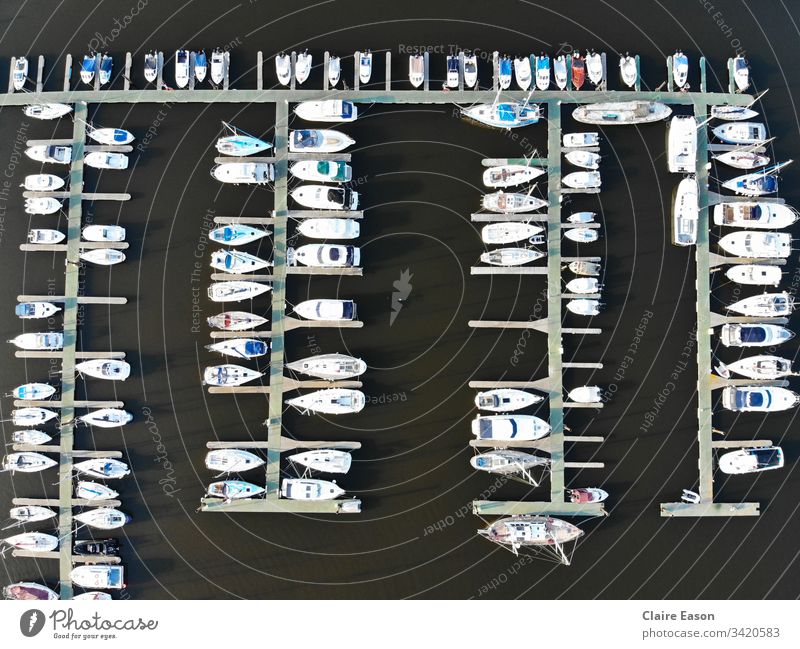 Luftaufnahme vieler Boote, die in einem Yachthafen anlegen, gegen dunkles Wasser, erstellt mit einer Dji-Kamera. Jachthafen Segeln Decks Küstenstreifen Seeküste