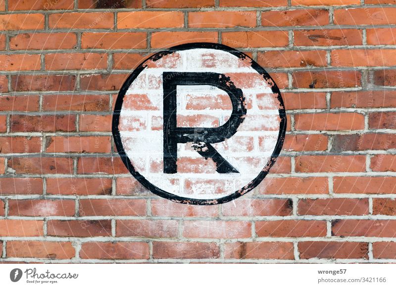 Großes schwarzes R auf weißem Grund an einer Backsteinmauer Buchstaben Farbfoto Tag Schriftzeichen Außenaufnahme Großbuchstabe Schild Ziegelmauer Gebäude