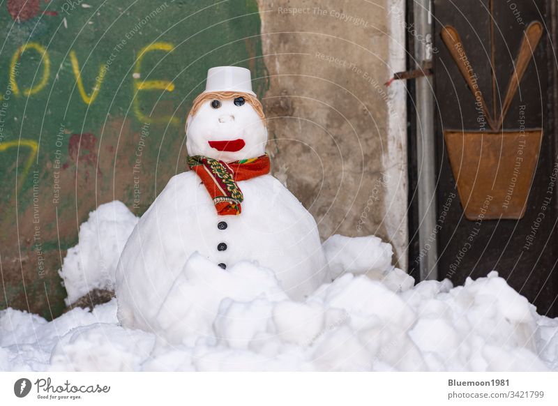 Schneemann mit Schal und Hut steht allein in der Gasse Gesicht gefroren Eis Winter Freizeit Schneemann machen spielerisch weiß Winterzeit Verschlussdeckel